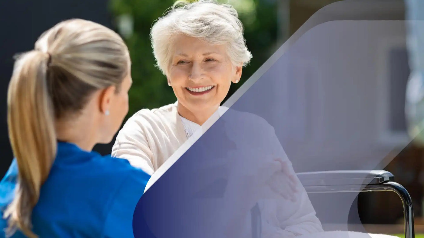 Eine ältere Frau im Rollstuhl, die einem Pfleger lächelt.