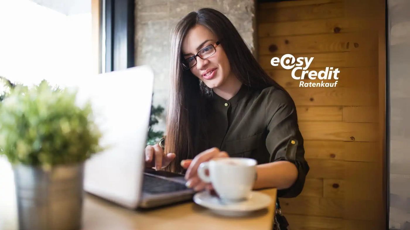 Frau mit langen dunklen Haaren und Brille tippt auf einem Laptop.