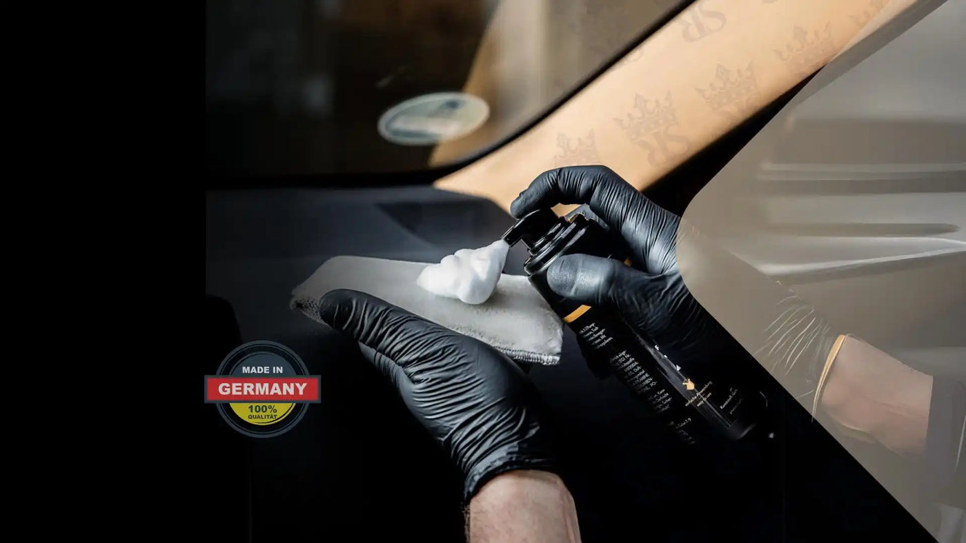 Eine Person mit schwarzen Handschuhen, die eine weiße Substanz aus einer Sprühflasche auf ein Polierpad aufträgt.