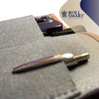 Eine smart tasche mit einem eleganten metallischen stift in lila und gold auf grauem stoff liegt